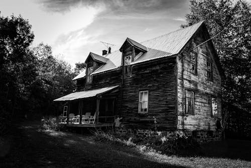 Grayscale Photo of Old Wooden House Near Trees