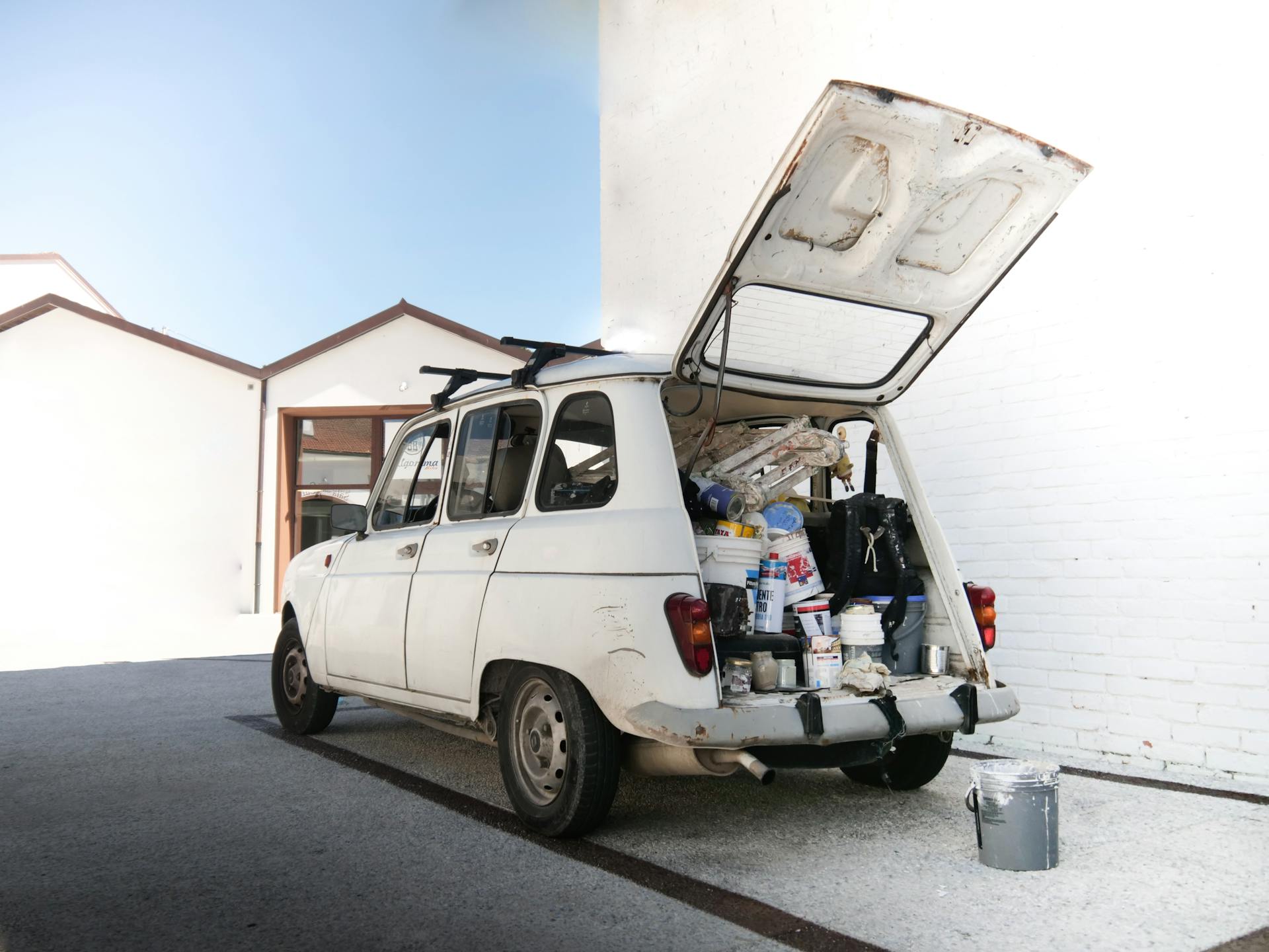 White Van Filled with Paint Cans Parked Beside White Building