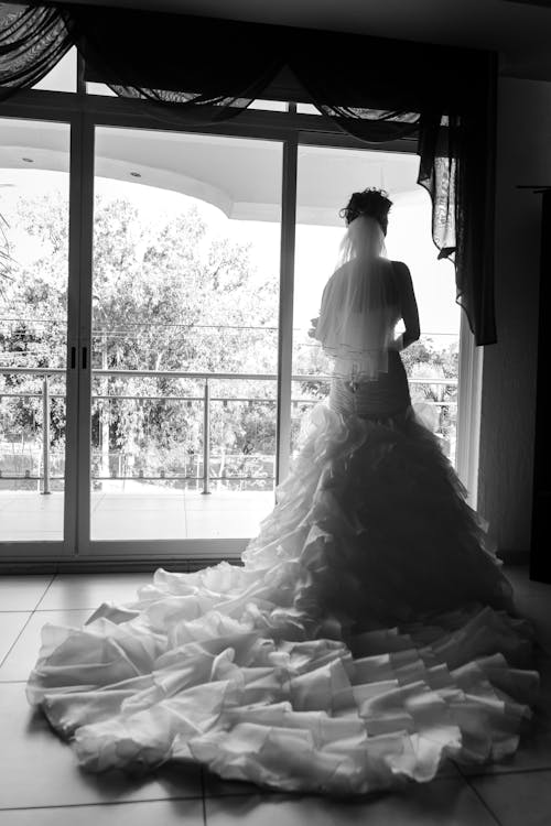 Free Woman in Wedding Dress Standing Near Window Stock Photo