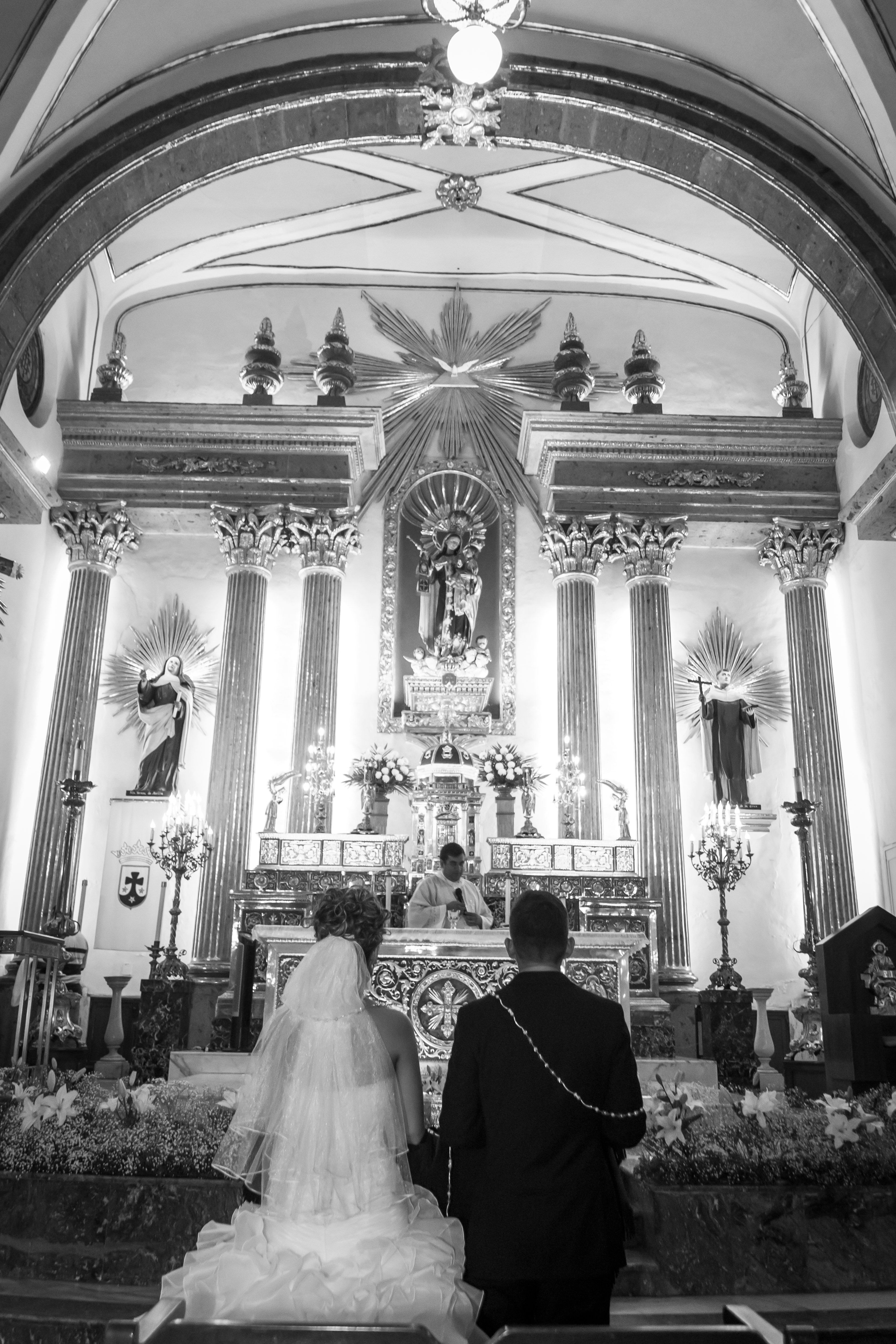 一对夫妇在经典教堂的黑白祭坛前，由牧师引导交换誓言