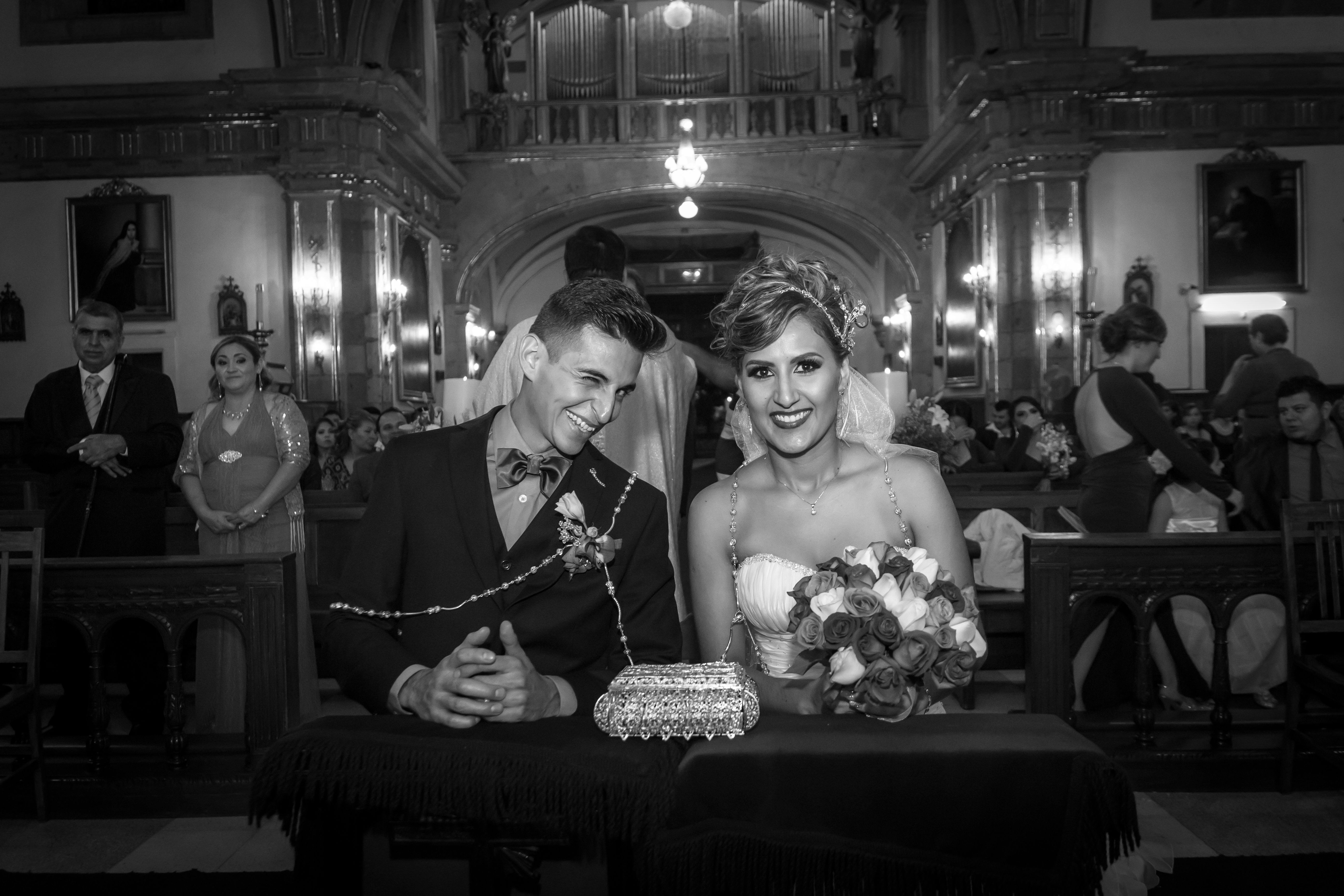 A joyful bride and groom during their wedding ceremony in a historic church, captured in black and white.