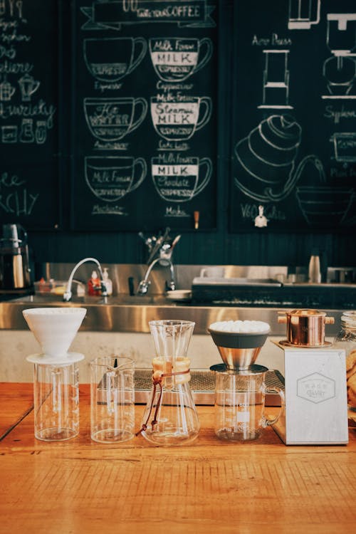 Free Glass bottles with various types for brewing coffee placed on table with menu and sink on background in cafe Stock Photo