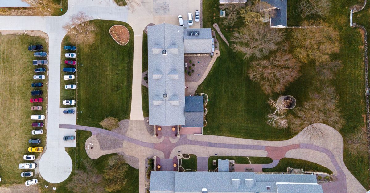 Top-down drone shot of residential area with parked cars and green lawns.
