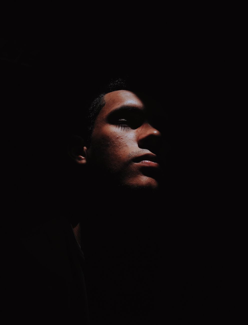 Dramatic side-profile portrait of a man with dark shadows and moody lighting.. dramatic, side, profile