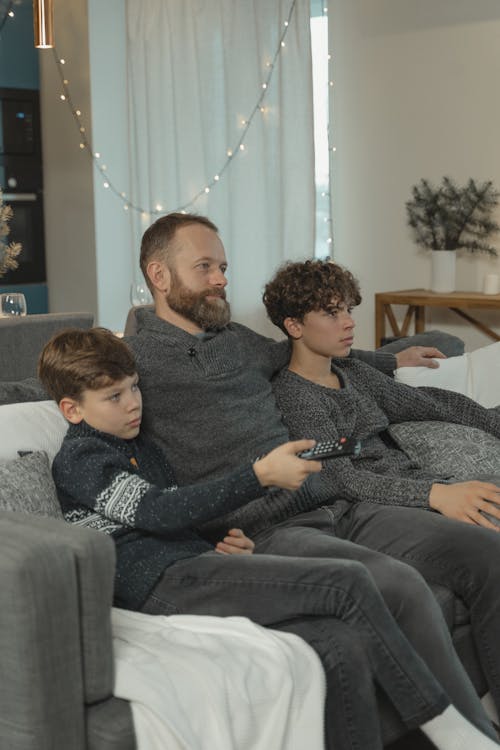 Free Father and Siblings sitting together on a Couch  Stock Photo