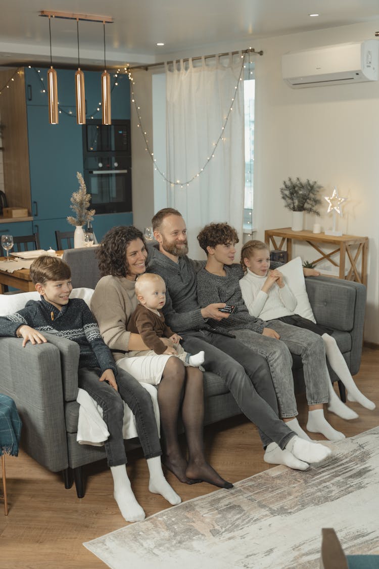 A Family Sitting On The Sofa Watching TV