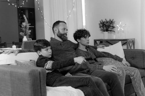 Monochrome Photo of Father and Siblings sitting together on a Couch 