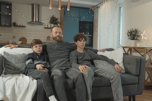 A Father and His Children Watching TV on a Sofa