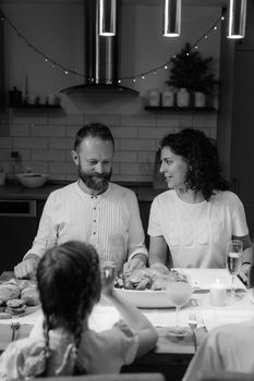 Intimate grayscale photo of a family enjoying a dinner together in a cozy kitchen setting.