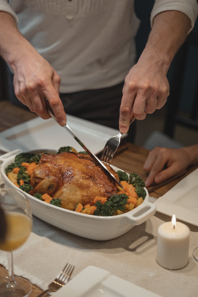 A Person Cutting A Roast Chicken