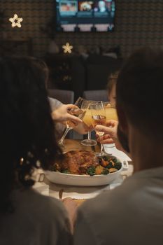 A group of people raising glasses in a toast over a beautifully set table with roasted turkey.
