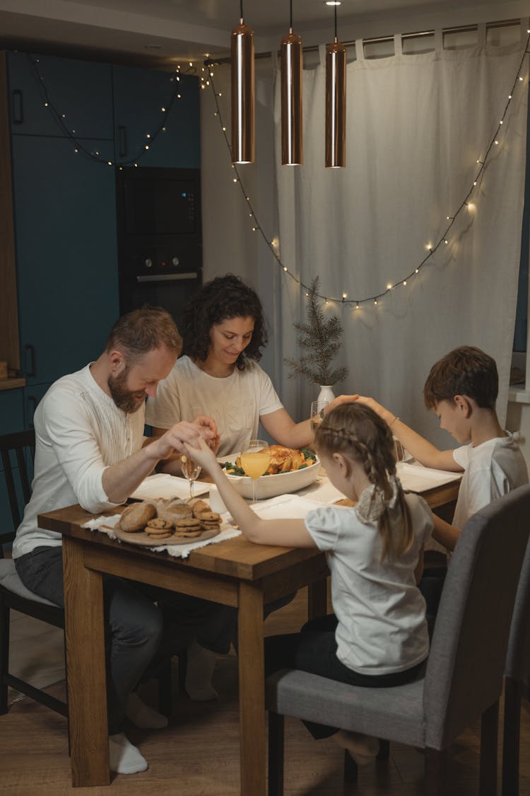 A Family Holding Hands In Reciting A Prayer