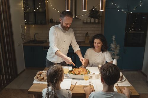 Free Warm family dinner gathering with turkey, cookies, and festive lights. Stock Photo