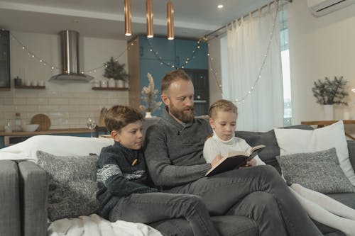 Free A Father Reading a Book Together with His Children Stock Photo