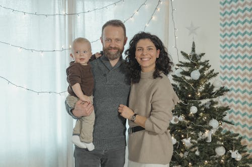 Free A Couple and Their Child Beside a Christmas Tree Stock Photo