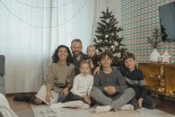 A family posing cheerfully indoors next to a Christmas tree.