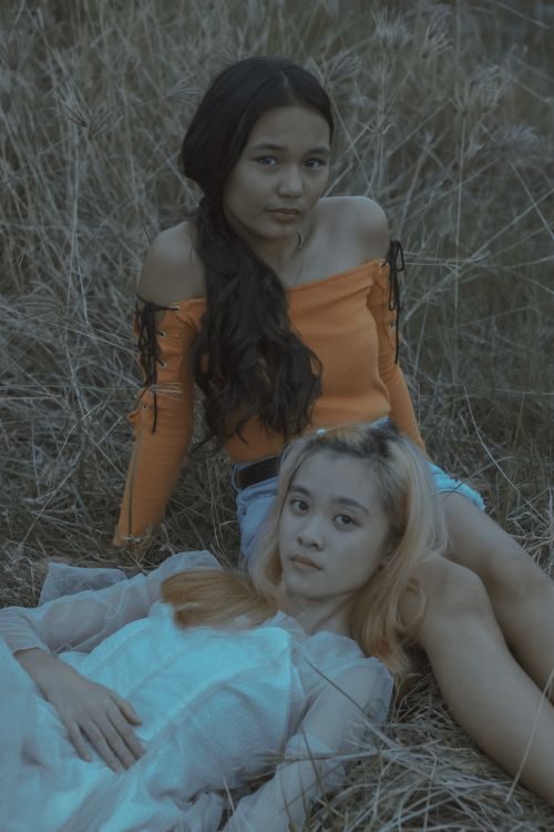 Free Two young women relax in a field, showcasing casual fashion in natural surroundings. Stock Photo