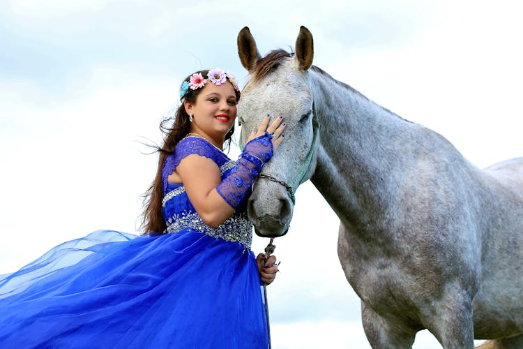 A Woman In A Blue Gown Beside A Horse