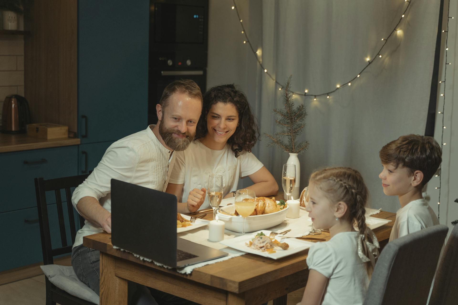 Family enjoying a Christmas dinner with online video call, sharing holiday joy indoors.