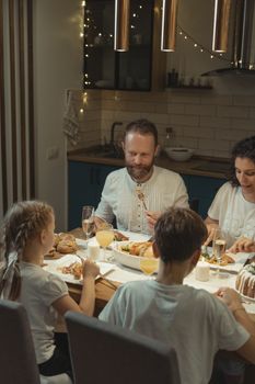 A family of four gathers around a festive table for a joyful Christmas dinner indoors.