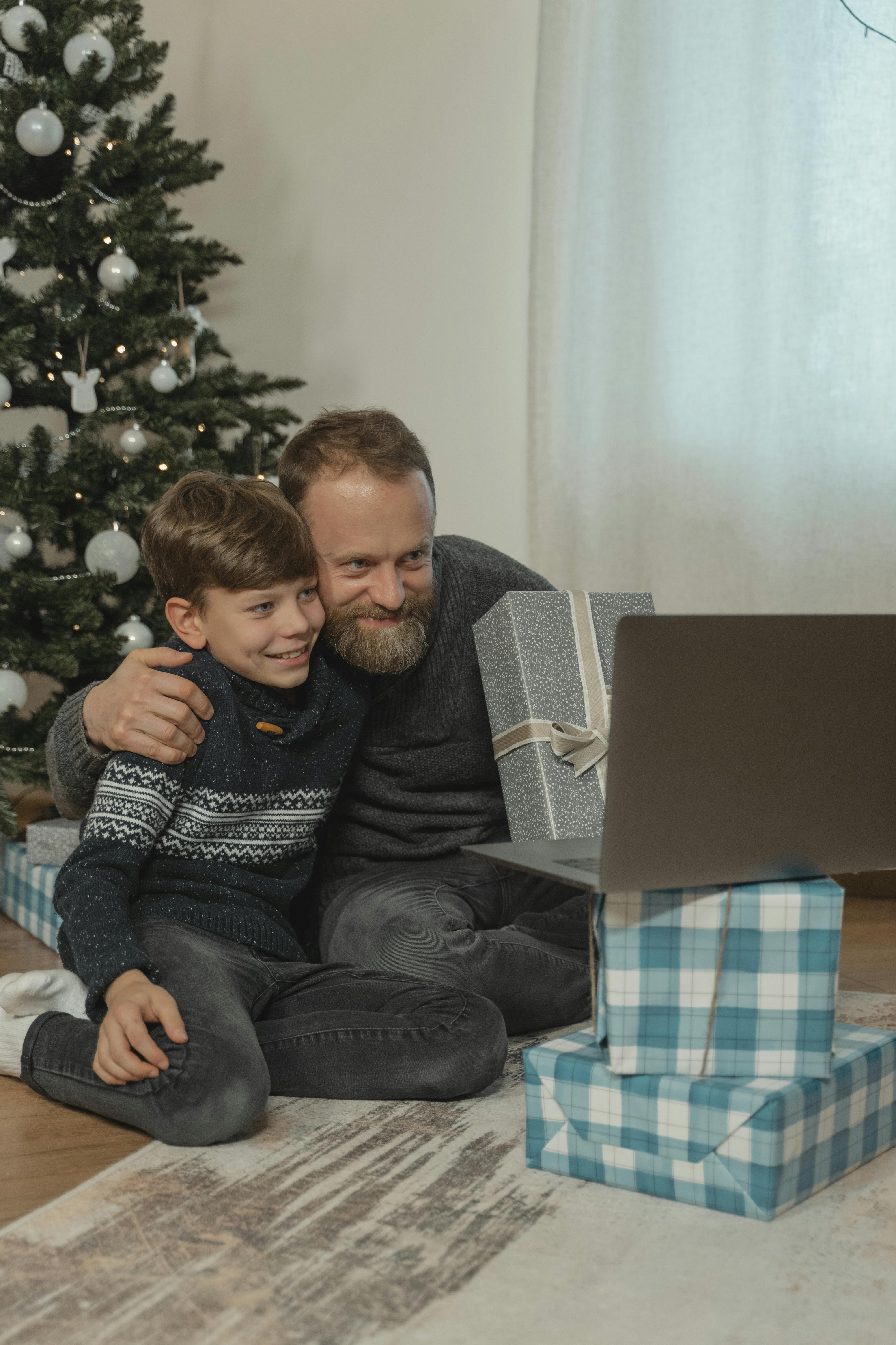 a father and son on a video call showing christmas gifts