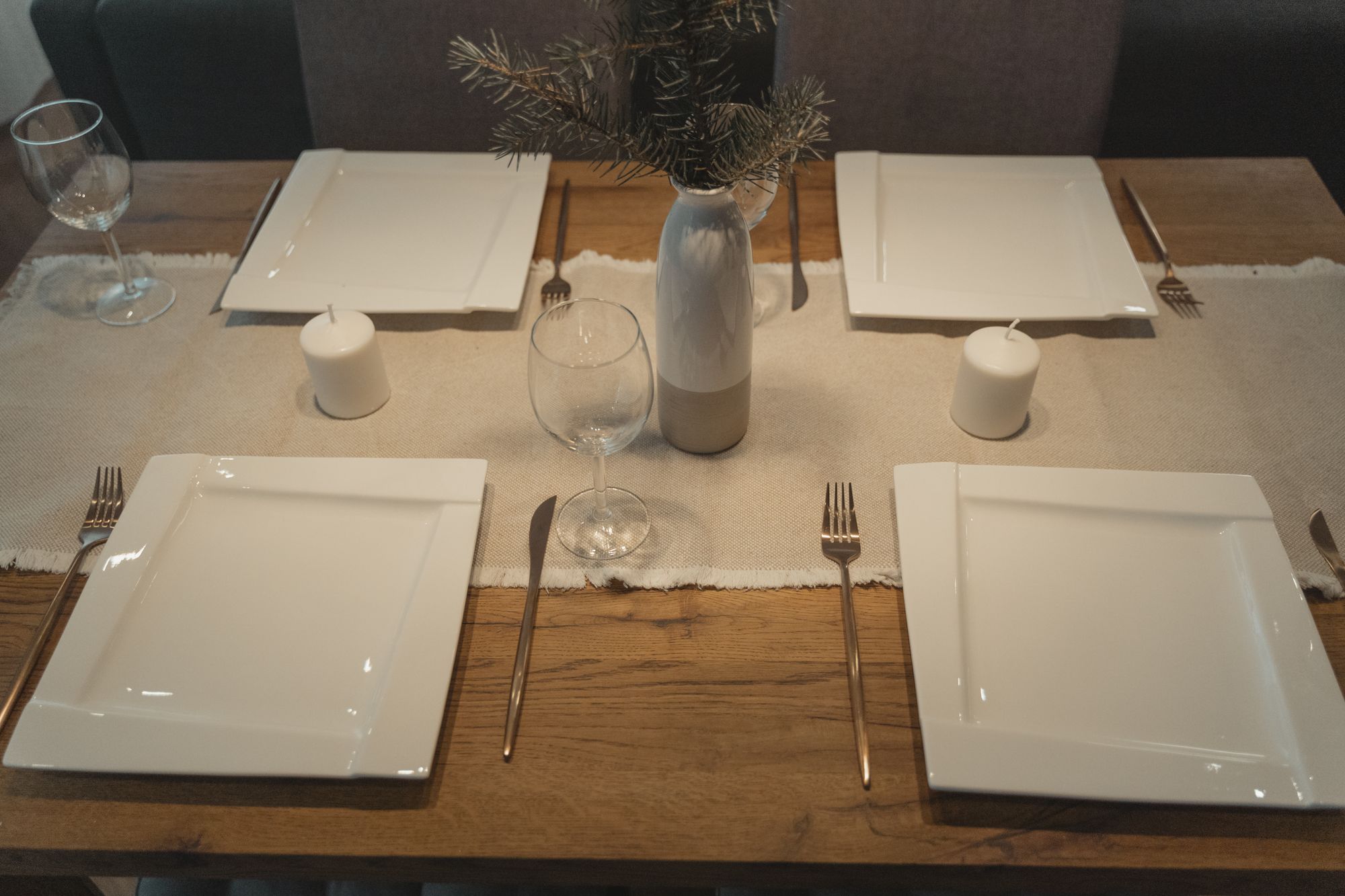 Dinner table prepared with white plates glassware and cutlery for four