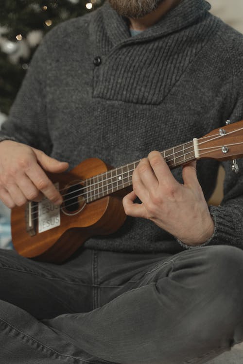 A Man in Gray Sweater Playing a Ukulele