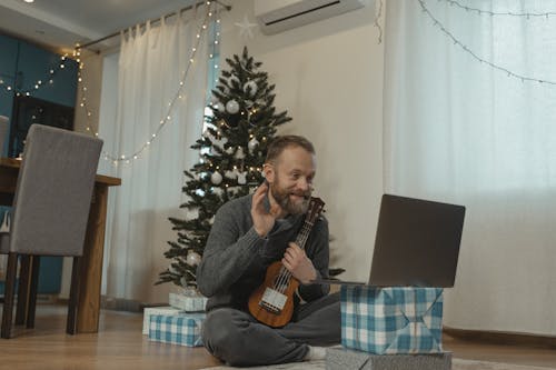 Man in Gray Sweater Holding a Ukulele While in a Video Call