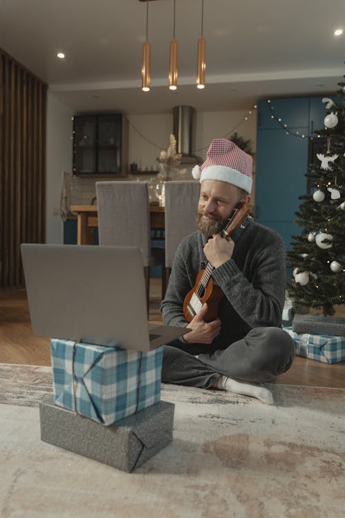 Free A Man Holding a Ukulele While in a Video Call Stock Photo