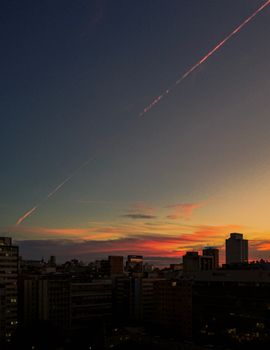 Dramatic city skyline captured at colorful sunset with high-rise buildings and vibrant clouds.