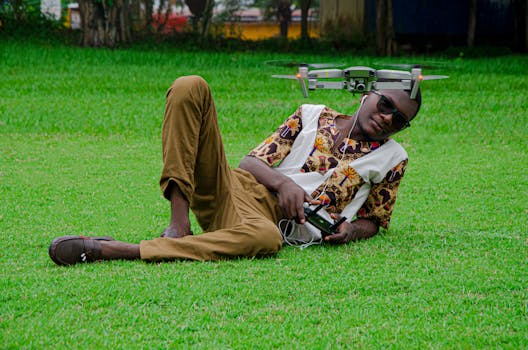 African man in vibrant shirt controls drone in a sunny Brazzaville park.