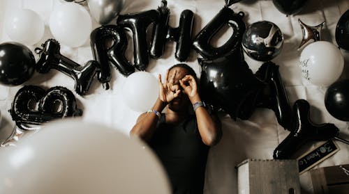 Free A Man Lying Down with Black and White Birthday Balloons Stock Photo