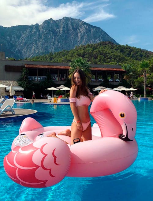 Girl in Bikini on Inflatable Pink Flamingo in Pool