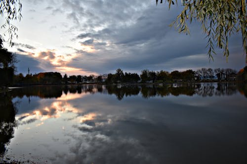 Body of Water Near Trees Under Dark Cloudy Sky