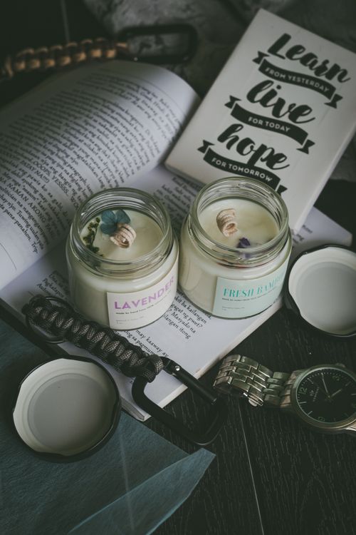 Free A tranquil reading nook with scented candles, an open book, and a wristwatch. Stock Photo