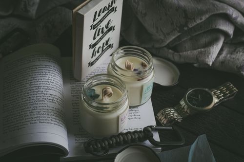 Free A comforting scene featuring books, scented candles, and a wristwatch, perfect for a peaceful reading time. Stock Photo