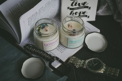 Free A cozy scene featuring aromatic candles, an open book, and a watch, perfect for relaxation. Stock Photo