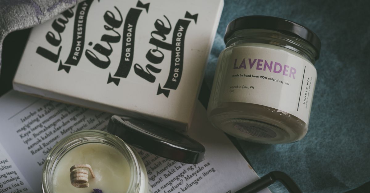Scented candles in glass jars styled with books, an example of home fragrance products that need careful fulfilment and shipping