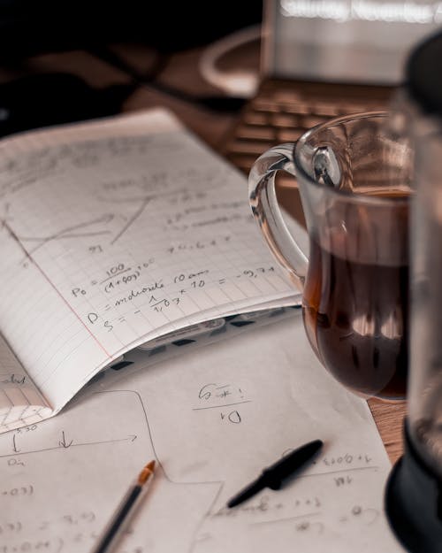 Free Papers With Equations Beside A Glass of Tea Stock Photo