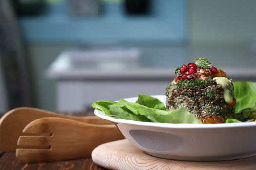 Delicious and healthy quinoa salad topped with pomegranate, mint, and a creamy dressing on a fresh lettuce bed.
