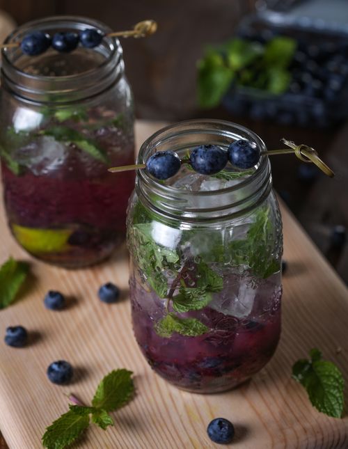 Free Close-up of refreshing blueberry mojitos with mint leaves in mason jars on a wooden board. Stock Photo