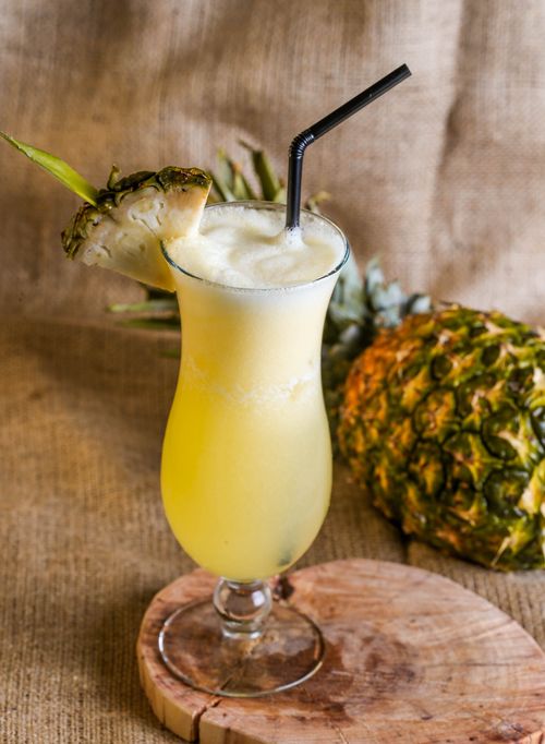 Free Chilled pineapple juice in a glass with a straw and sliced pineapple garnish. Stock Photo