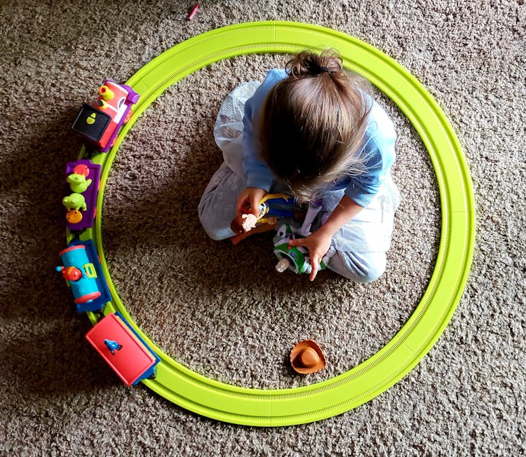 Child Playing A Toy Train And Figures