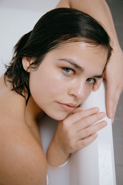 A close-up of an elegant young woman relaxing in a bathtub with a serene expression.