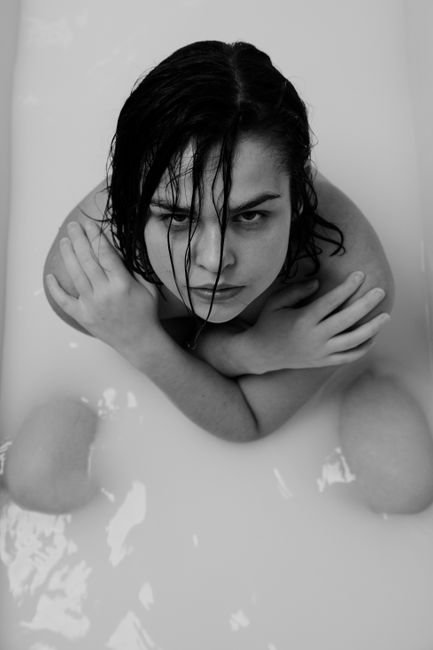 Woman in a black and white milk bath, showcasing self care and relaxation.