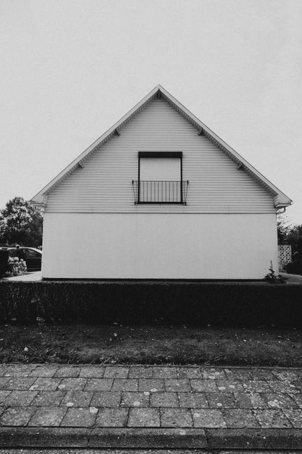 Monochrome image showcasing a simple yet elegant house facade with a triangular roof.
