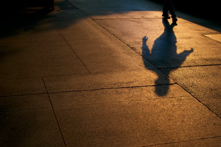 Shadow Of Person Walking On Concrete Pavement