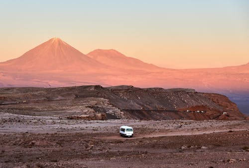 Van in Barren Land and Scenic Desert Mountains in Background