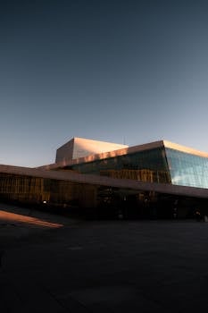 Capture of the Oslo Opera House showcasing its modern architectural design under a sunset sky.