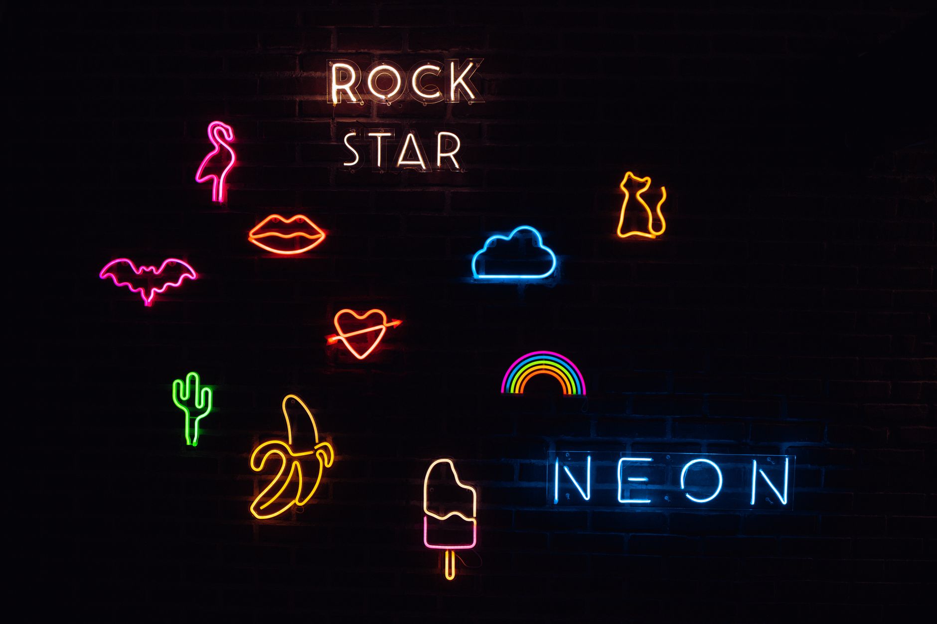 Colorful neon signs featuring fun shapes and phrases on a black wall.